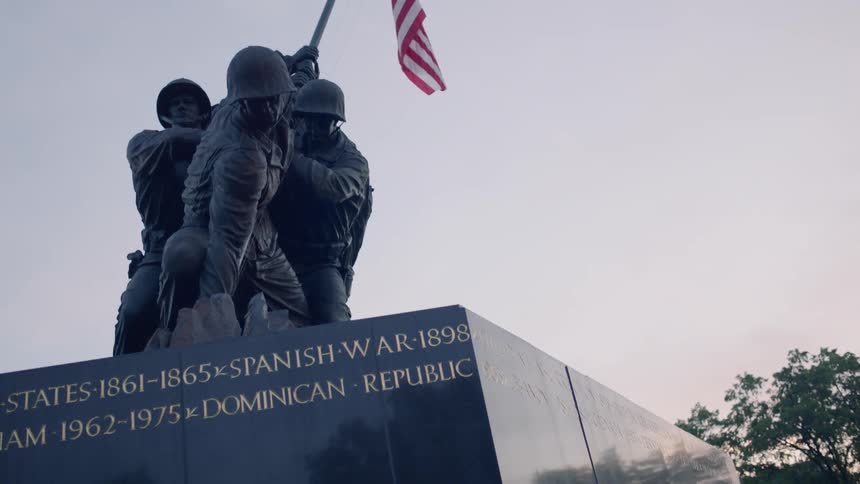 A war memorial monument is displayed with an american flag