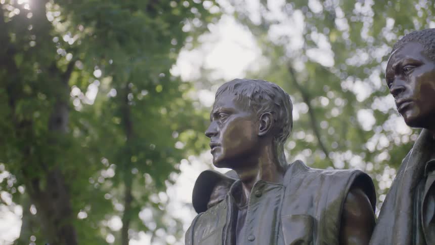 A bronze statue stands in a park