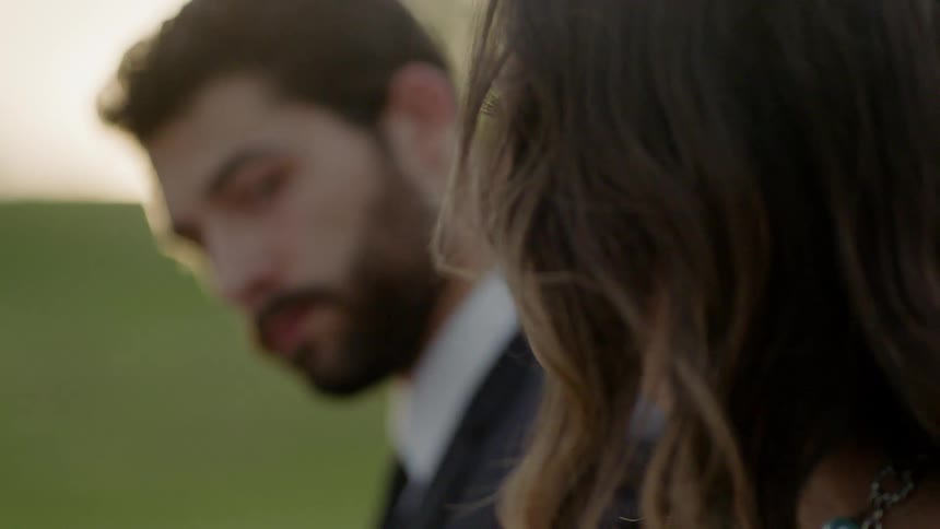 A man and woman sit outside and look at each other