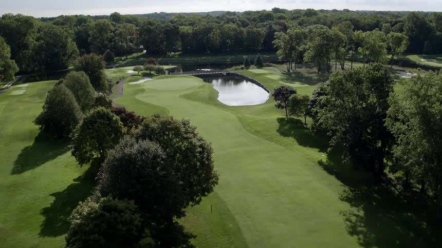 A golf course with a lake and trees is flown over