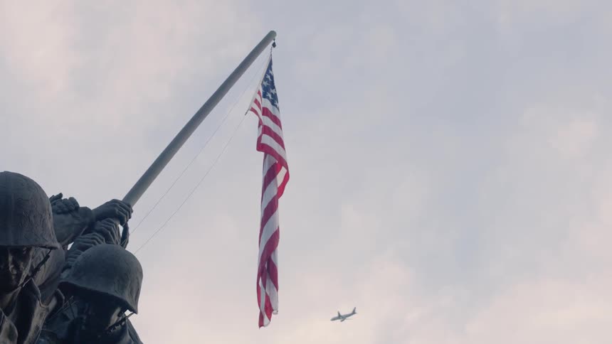 An airplane flies in the sky above a war memorial
