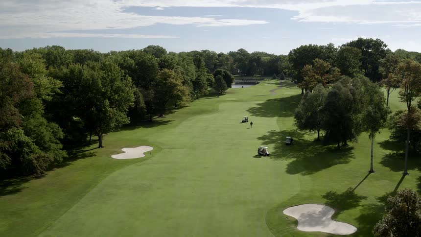 Golf carts are riding around a golf course