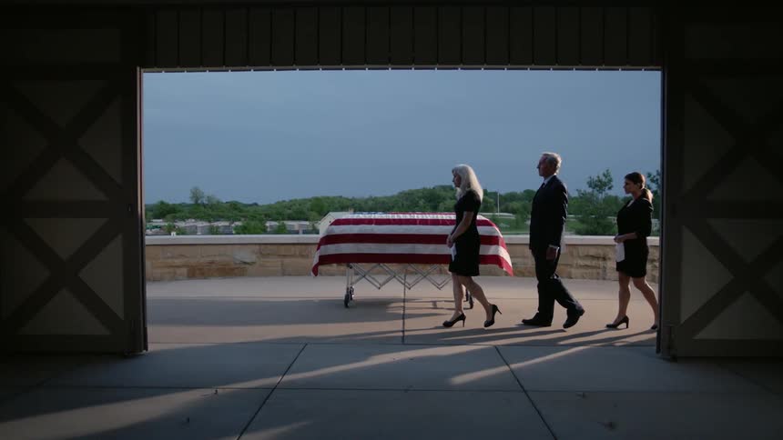 People walk past a flag draped casket