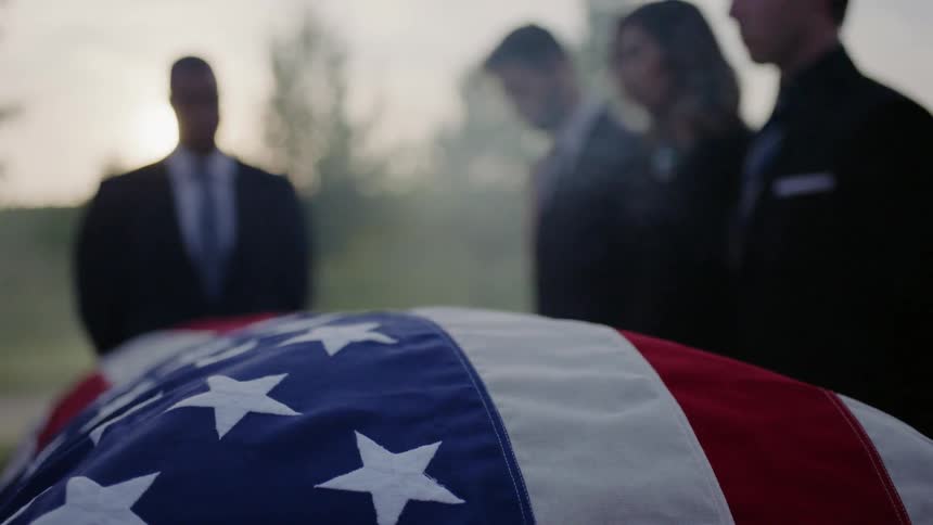 A group of people are gathered around a soldiers casket
