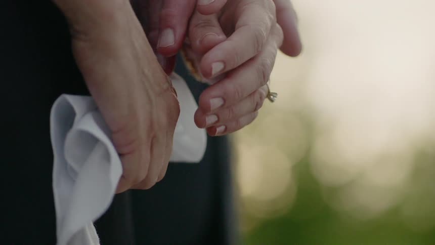 A man reaches for the hand of a woman holding a handkerchief