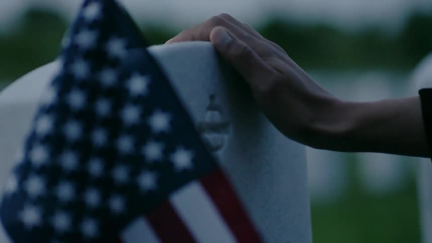 Someone places their hand on top of a soldier's tombstone