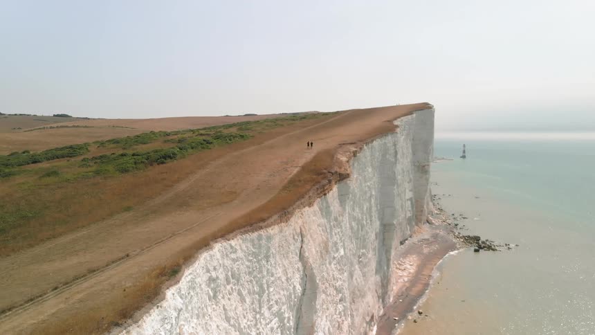 A seaside cliff is being walked on by two people