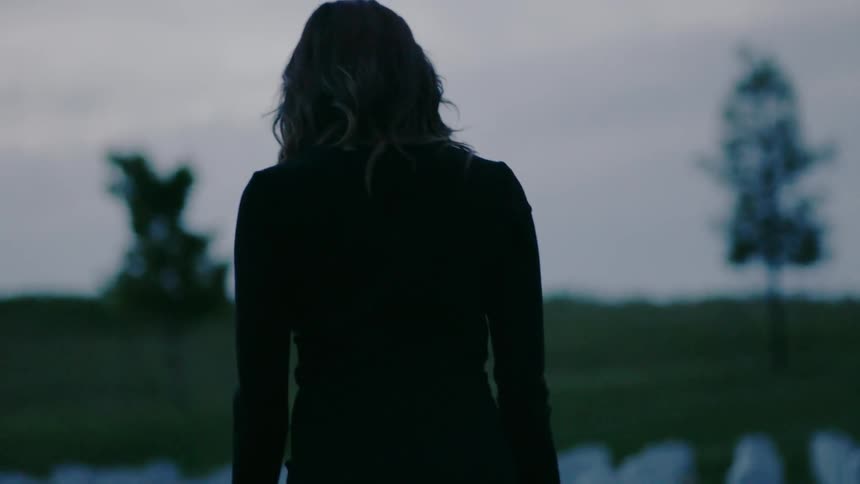 A woman walking outside at sunset in a graveyard