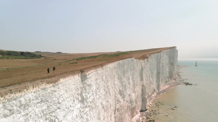 Two Athletes Running by White Cliffs on a Sunny Day