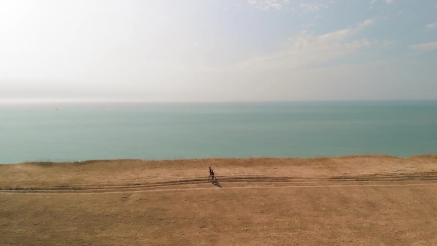 Two people jog near the shore