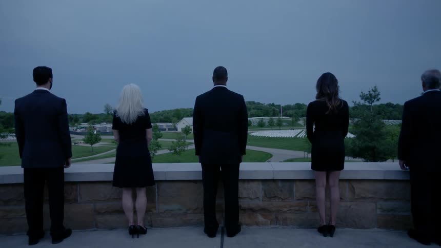 A group of people are standing on a balcony overlooking a park