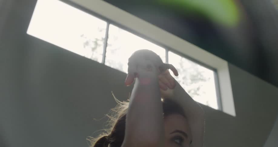 A woman dances under a window