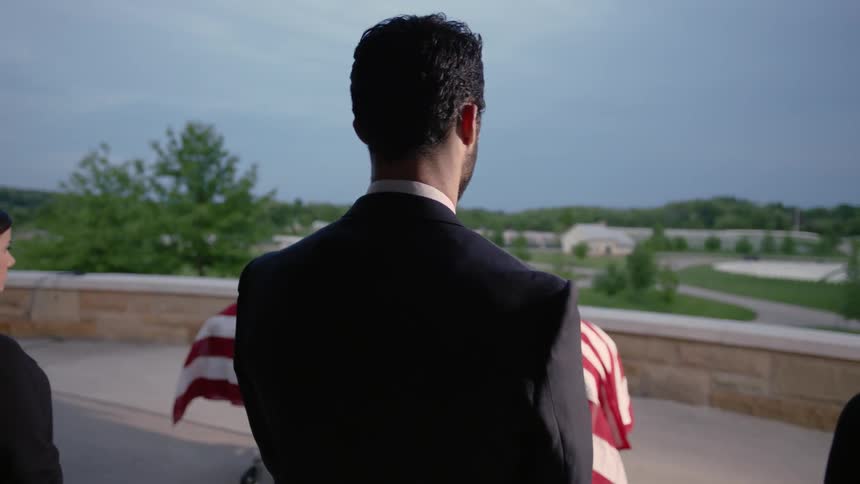 A group of people are standing next to each over looking at a flag covered casket