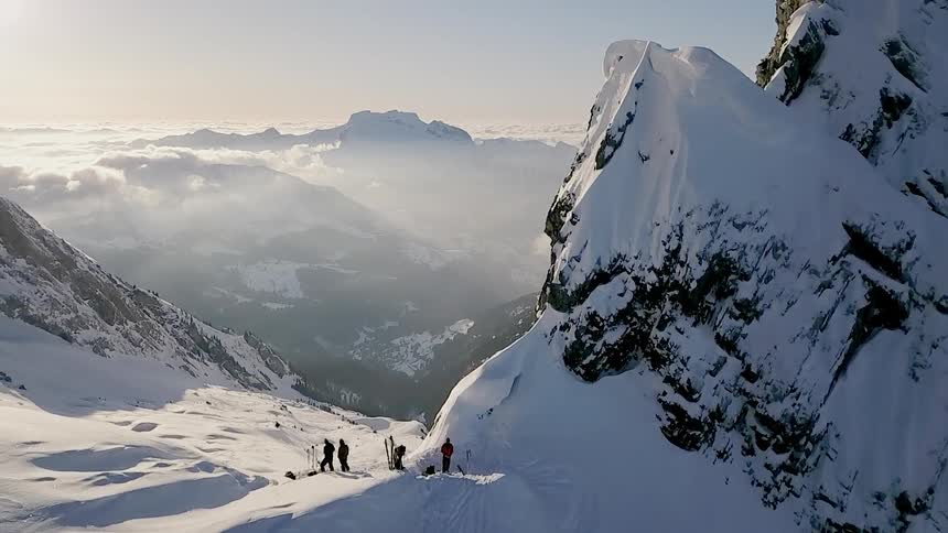 A group of people are standing on top of a snow covered mountain