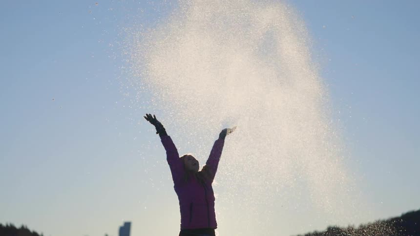 A woman throwing snow into the air.