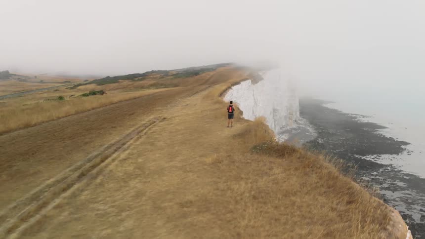 A man steps close to the edge of a cliff