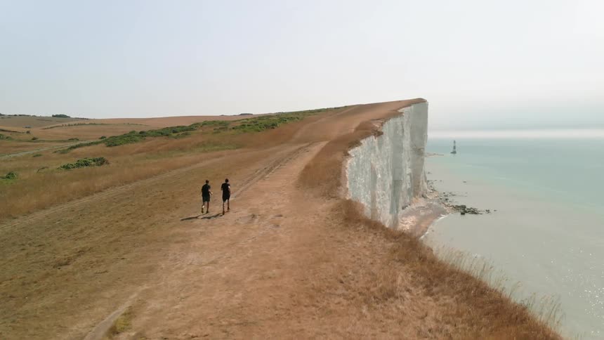 Two Athletes Running by White Cliffs on a Sunny Day