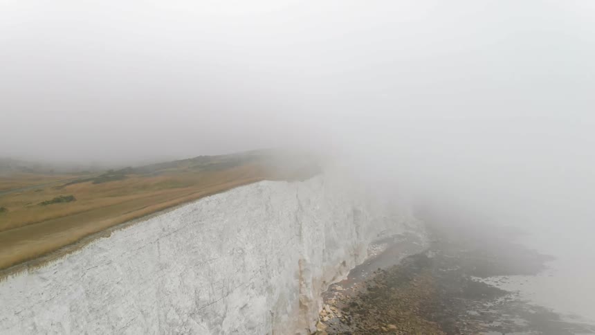 Fog covers the edge of a white cliff