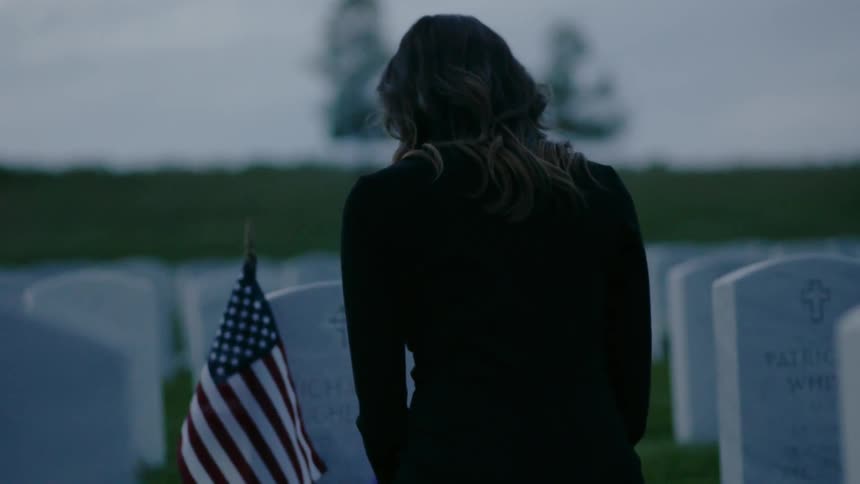A woman is standing in front of a soldiers grave