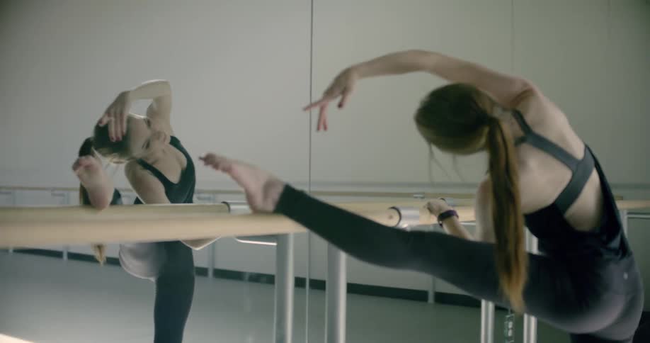 A woman is stretching against a mirror