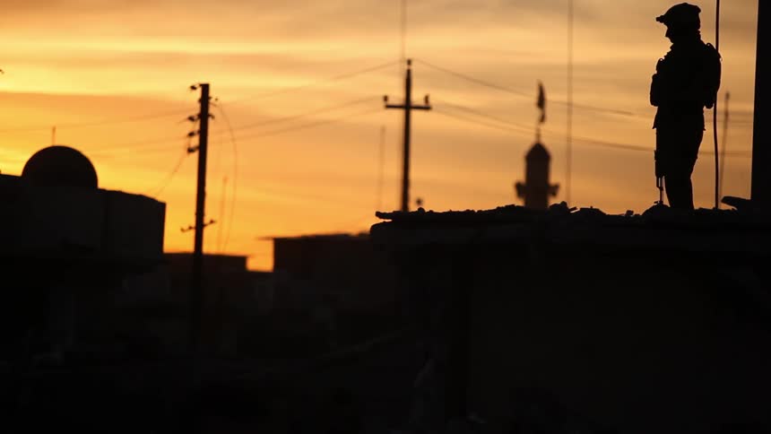 A man is holding a gun with the sun setting behind him