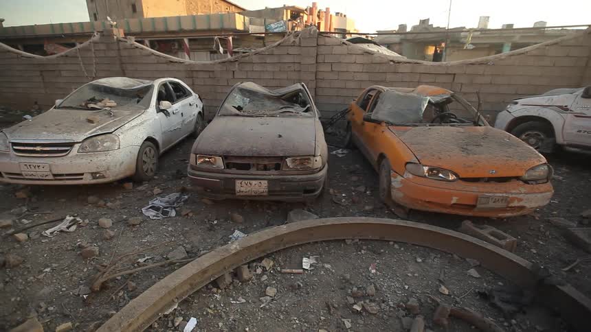 Damaged cars near a brick wall
