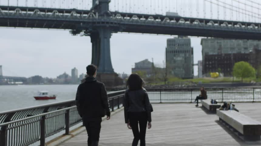Man and woman walking on sidewalk next to the water