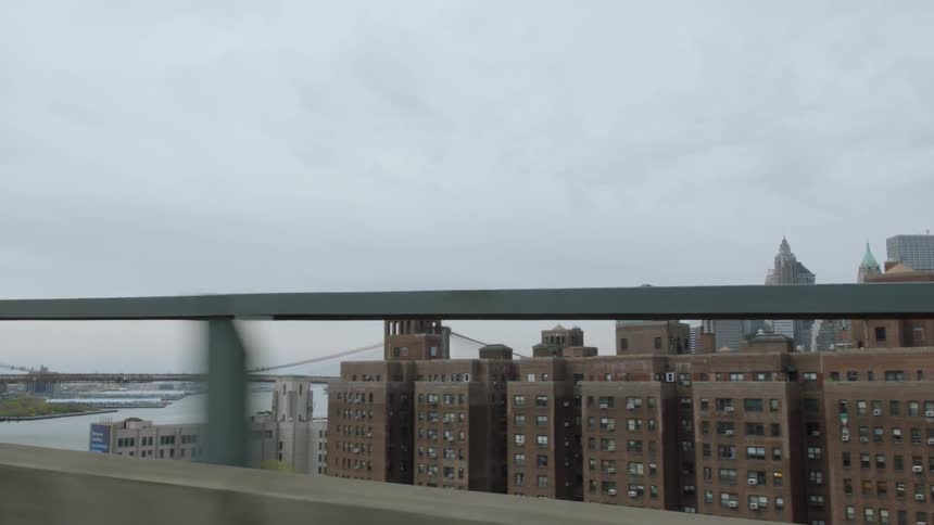 A vehicle passes over a bridge by tall apartment buildings
