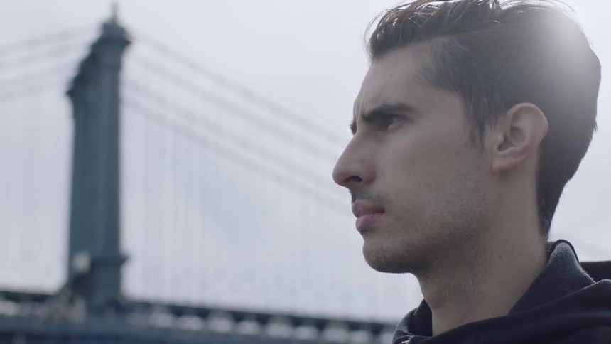 Man standing near a suspension bridge looking out
