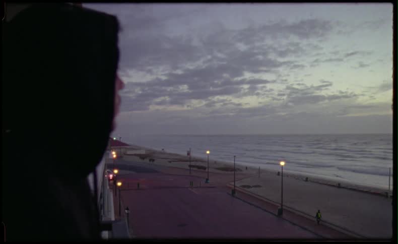 Man in hoodie watching to the ocean and beach