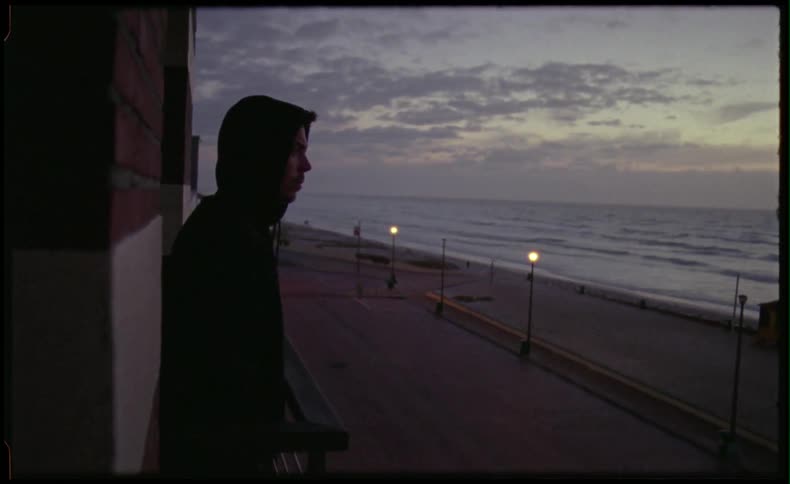 Contemplative man watching out over the beach and ocean at sunset