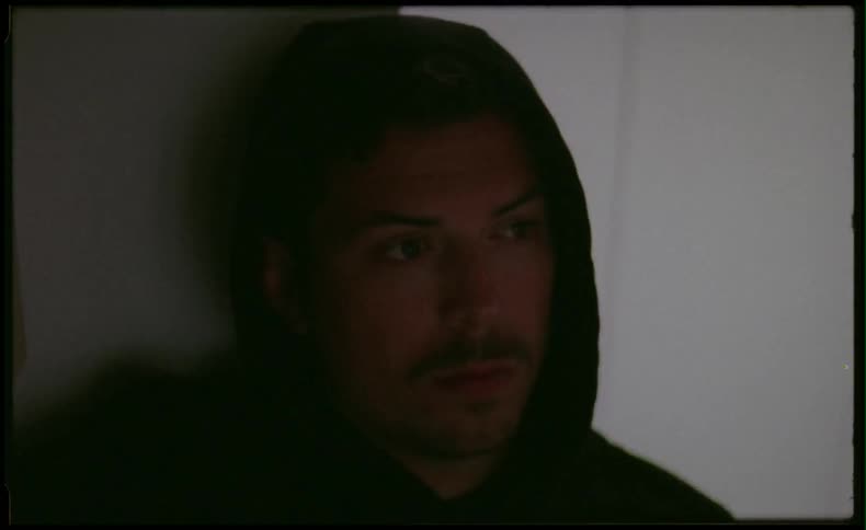 Man in room wearing a hood and turning a lamp on and off