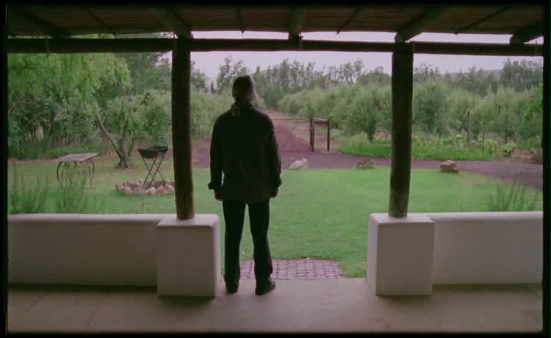 A man stands on a patio and walks outside