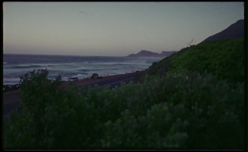 Waves crashing on beach by the road during sunset
