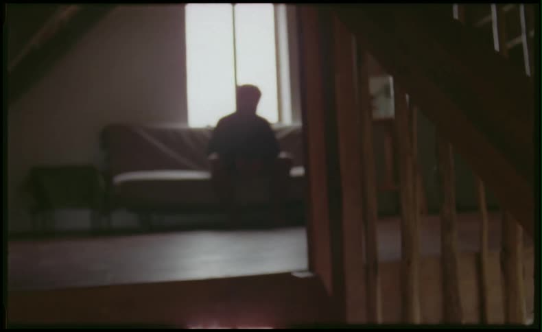 Man sits on a couch near stairs
