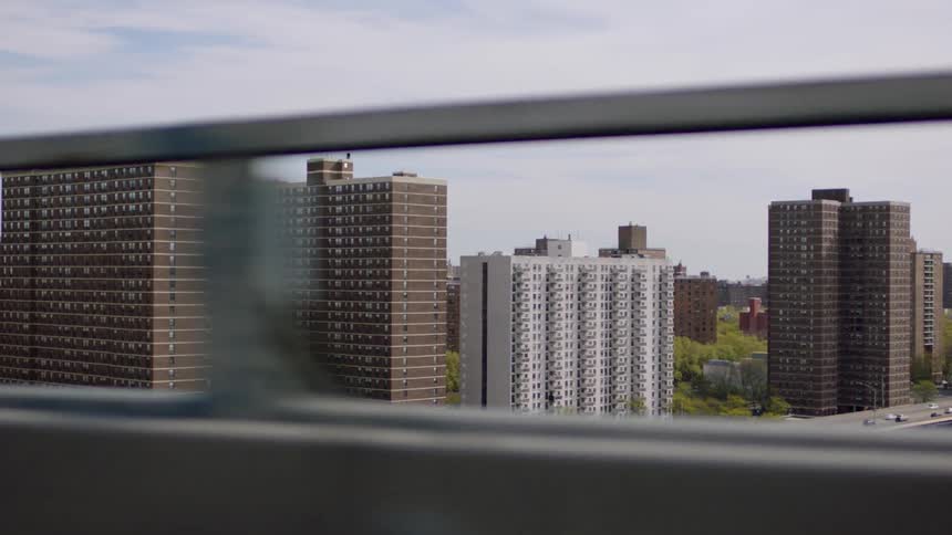 A vehicle passes over a bridge by tall apartment buildings