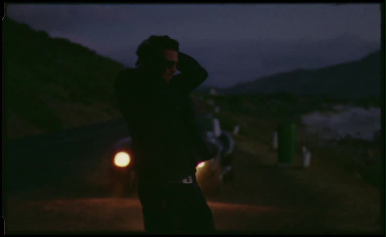 Man in front of classic sports car by the beach and mountains