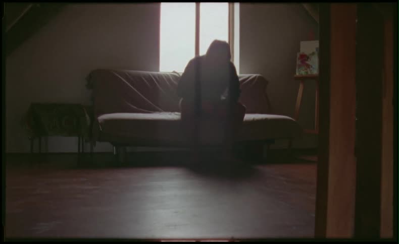 Man sits down on couch in front of a window in a house