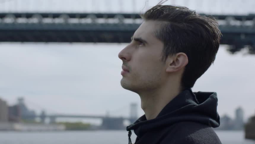 Man standing by bridge and water looking out