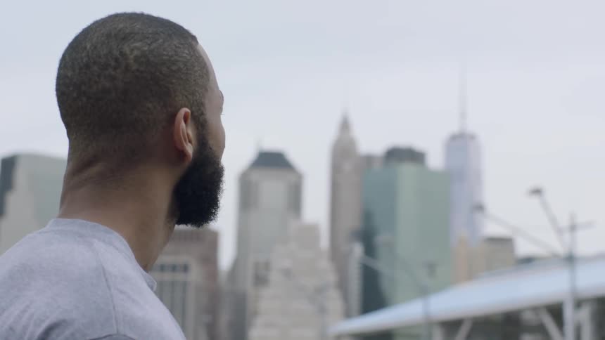 A man stares out at tall city buildings