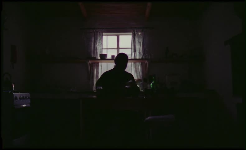 Man sitting at desk in front of a window in a dark room