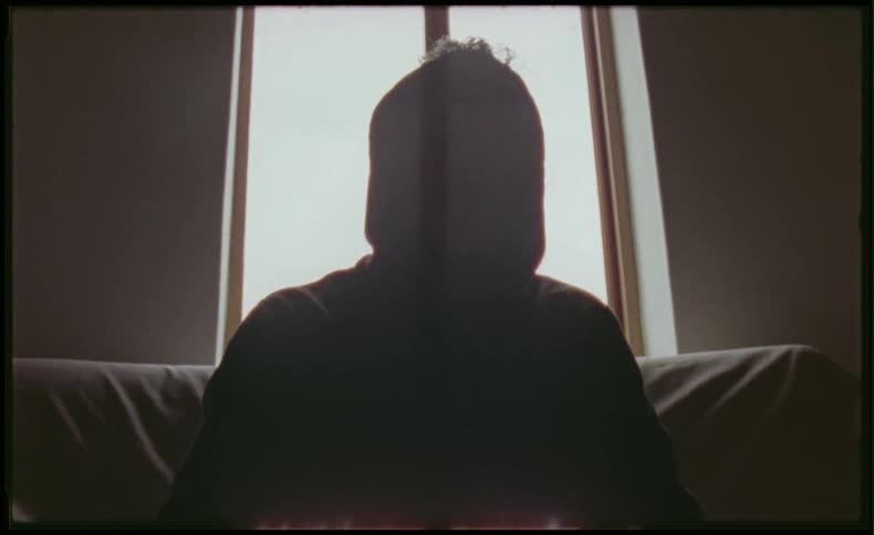 Person in hoodie sitting in front of a window