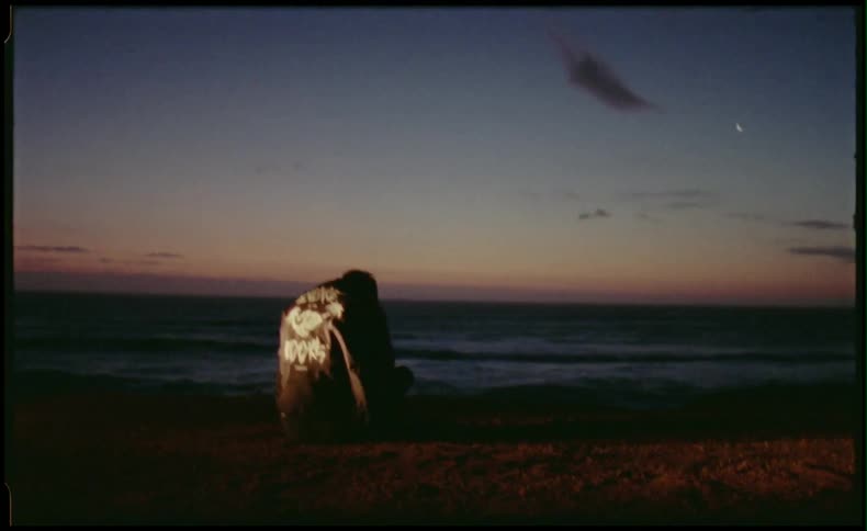 Friends sitting on beach at night in front of their car headlights