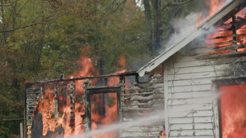 A firefighter sprays water on a burning house