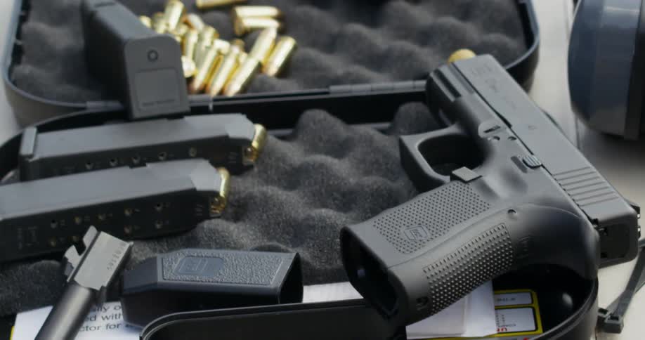 A gun and gun clips rest on a gun case