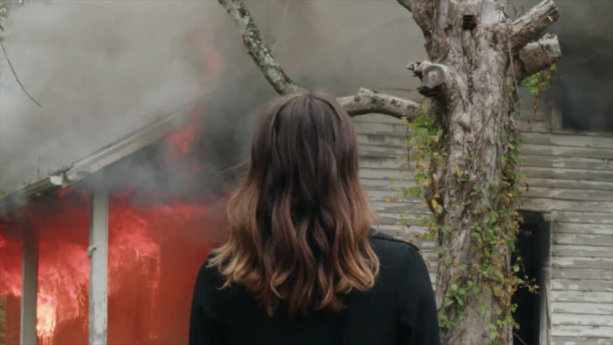Woman watches a house on fire