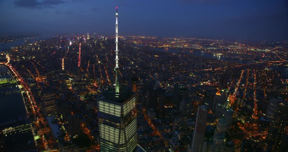 A tall city tower illuminates the night sky