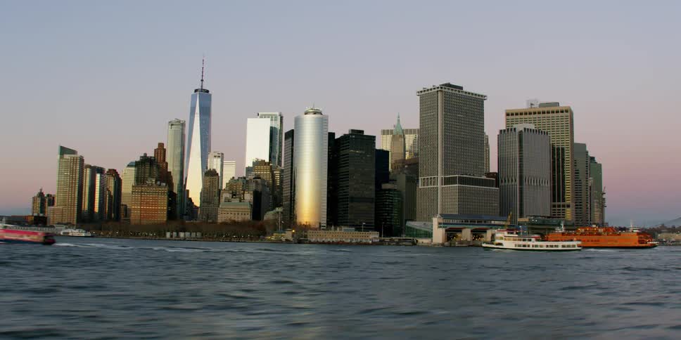 Tall city buildings tower into the sky by the water