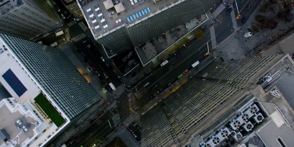 Vehicles travel on a city road near tall city buildings