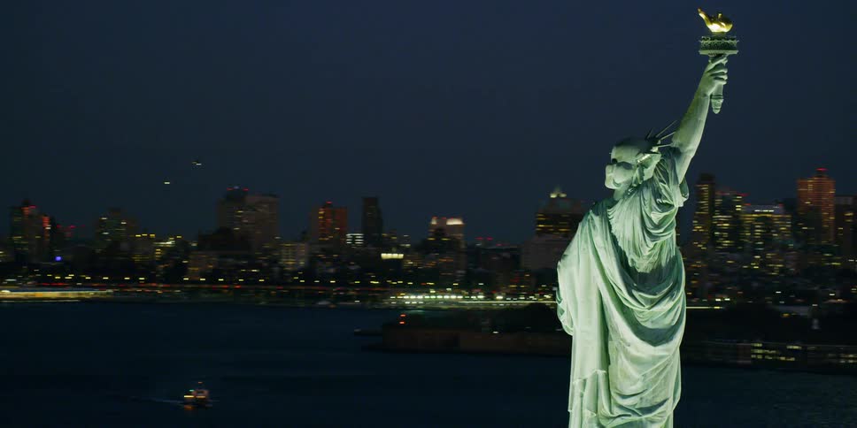 The statue of liberty illuminates in the night sky